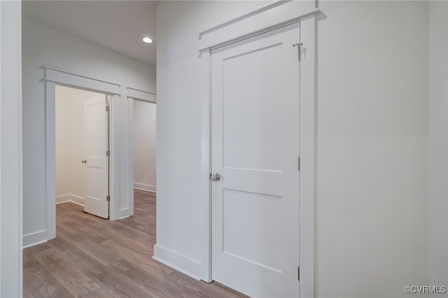 corridor featuring baseboards, light wood-style flooring, and recessed lighting