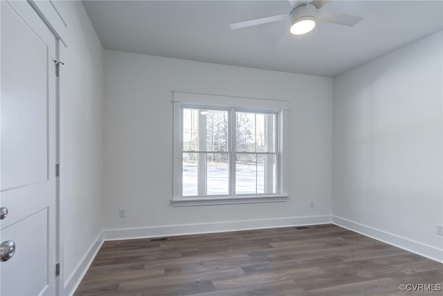 unfurnished room featuring a ceiling fan, visible vents, baseboards, and dark wood-type flooring