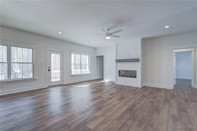 unfurnished living room featuring a fireplace, baseboards, dark wood finished floors, and recessed lighting