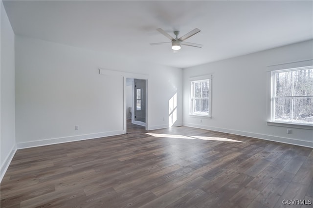 spare room featuring plenty of natural light, ceiling fan, and dark wood-type flooring