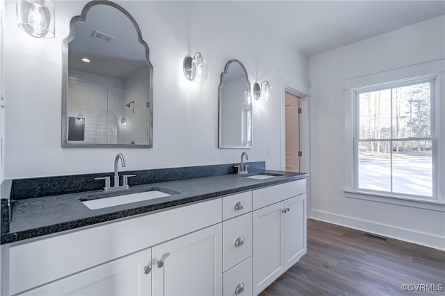 bathroom with double vanity, wood finished floors, a sink, and visible vents