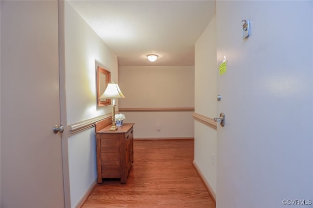 corridor with light wood-style flooring and baseboards