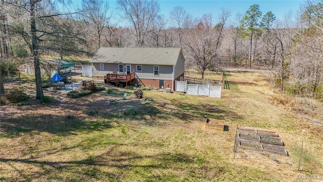 rear view of property with a lawn, a wooden deck, and fence