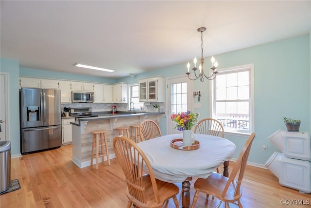 dining space featuring a notable chandelier, baseboards, and light wood-type flooring