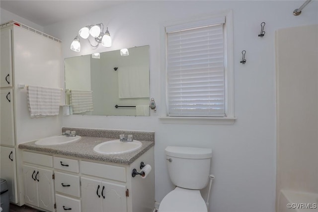 bathroom featuring double vanity, toilet, and a sink