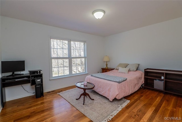 bedroom featuring wood finished floors, visible vents, and baseboards