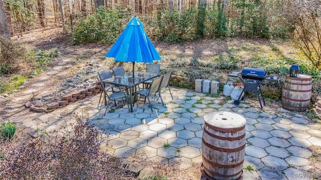 view of patio with outdoor dining space, a forest view, and a grill