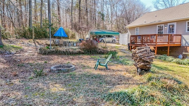 view of yard with a fire pit, a detached carport, and a deck