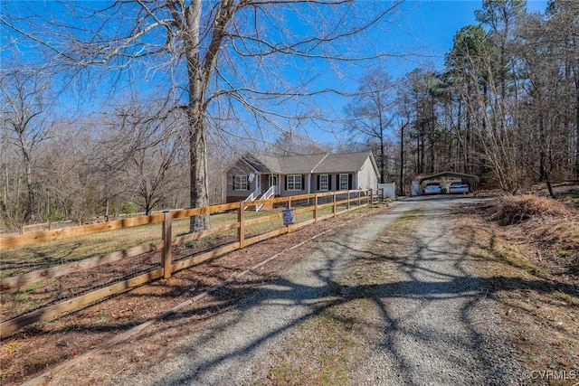 view of front of house featuring a fenced front yard, a detached carport, an outdoor structure, and dirt driveway