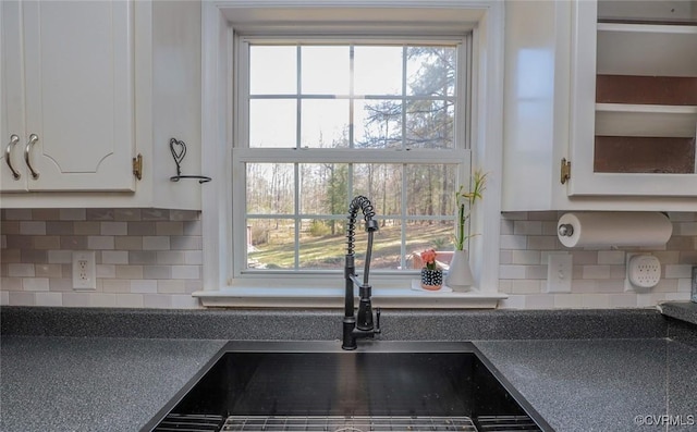 details with dark countertops, white cabinets, tasteful backsplash, and a sink