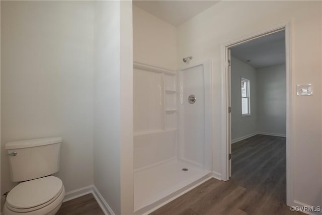 bathroom with a walk in shower, wood finished floors, toilet, and baseboards