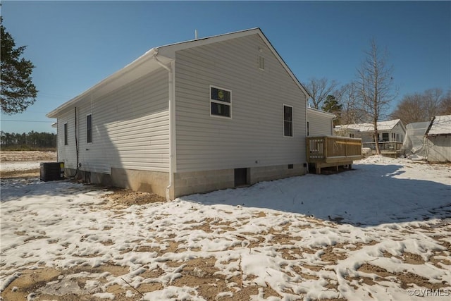 snow covered rear of property with cooling unit and a wooden deck