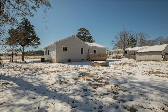 snow covered back of property with crawl space and a wooden deck