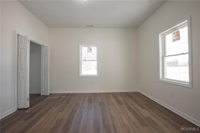 unfurnished bedroom with visible vents, dark wood finished floors, and baseboards