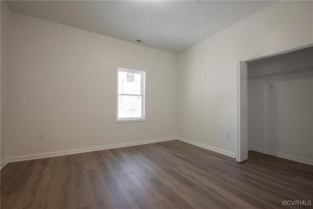 unfurnished bedroom with dark wood-type flooring, a closet, visible vents, and baseboards