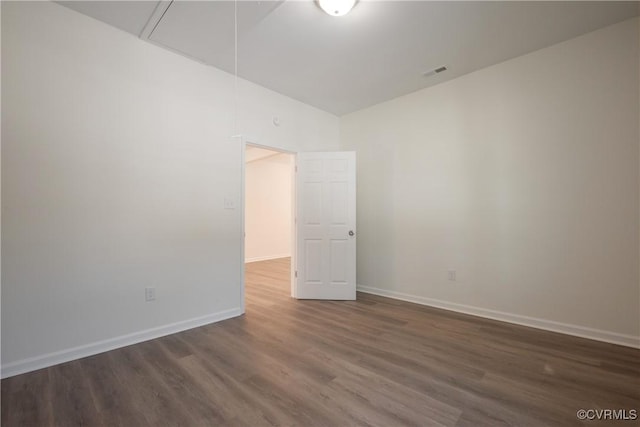 empty room featuring attic access, visible vents, baseboards, and wood finished floors