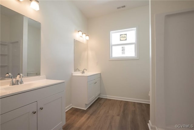 bathroom with two vanities, visible vents, a sink, wood finished floors, and baseboards