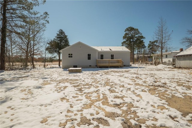 snow covered back of property featuring a deck