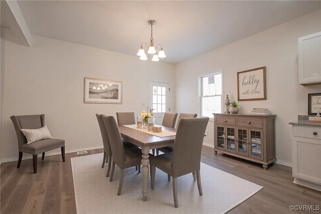 dining space featuring an inviting chandelier, baseboards, and dark wood finished floors