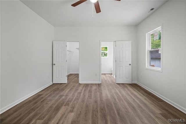 9214 River Rd, Chesterfield, VA 23803 - unfurnished bedroom featuring wood finished floors, multiple windows, a walk in closet, and ceiling fan