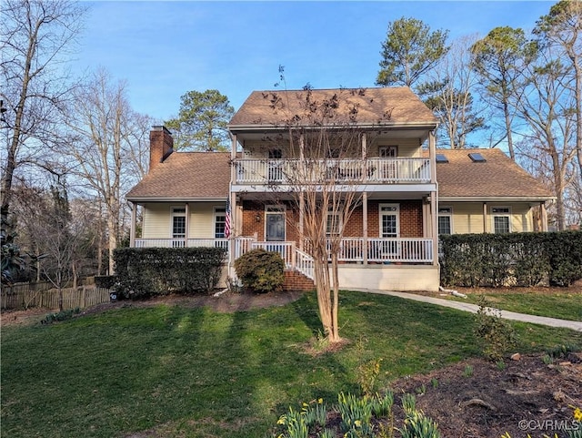 view of front of home with a chimney, a balcony, a porch, and a front yard