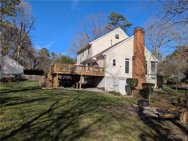 rear view of house featuring a yard, a deck, a chimney, and fence