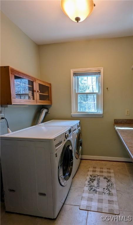 clothes washing area featuring light tile patterned floors, washing machine and dryer, and baseboards