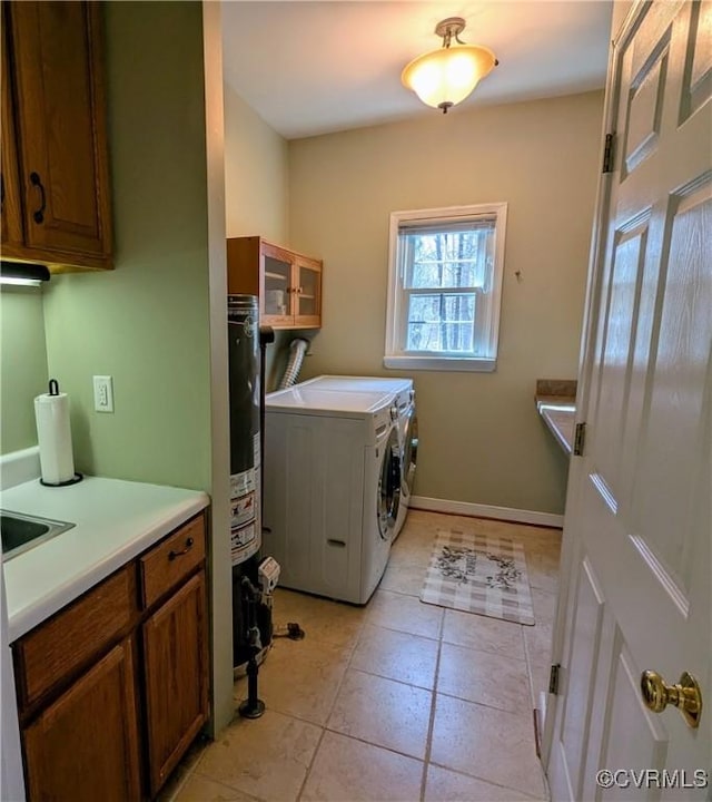 laundry area featuring washer and dryer, baseboards, cabinet space, and light tile patterned flooring