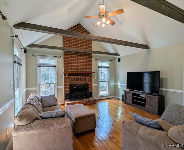 living room featuring a wealth of natural light, vaulted ceiling with beams, and wood-type flooring