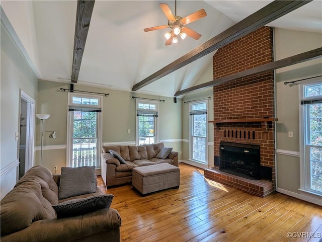 living area with a fireplace, vaulted ceiling with beams, and light wood finished floors