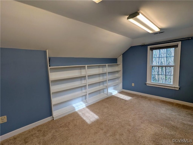 additional living space with visible vents, baseboards, carpet flooring, and vaulted ceiling