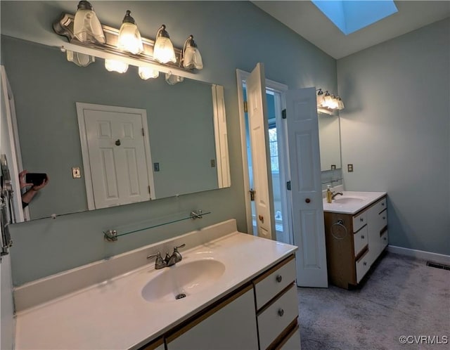 full bath with a sink, visible vents, two vanities, and a skylight