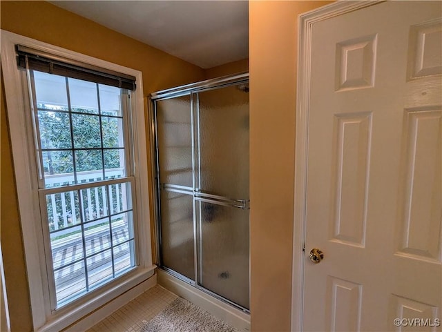 bathroom with a shower with door, tile patterned floors, and a wealth of natural light