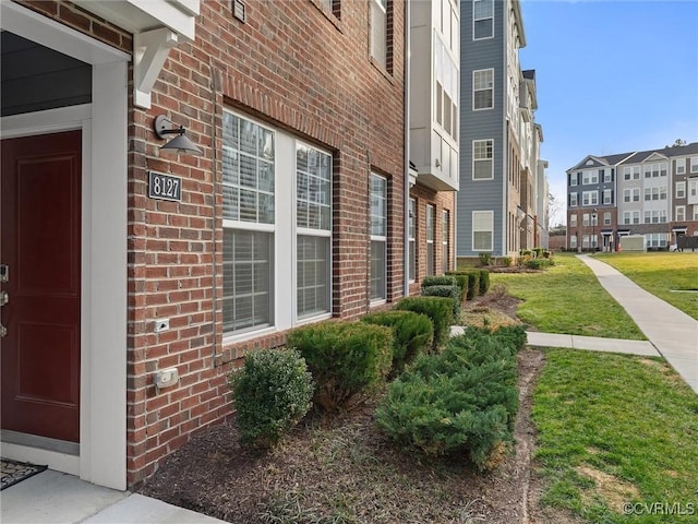 property entrance featuring brick siding and a lawn