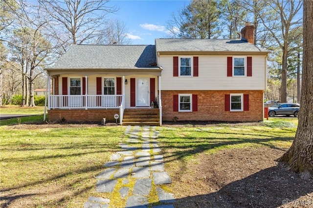 split level home with a chimney, a front lawn, a porch, and brick siding