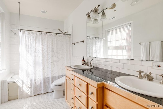 bathroom featuring visible vents, toilet, shower / tub combo with curtain, vanity, and backsplash