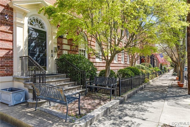 view of exterior entry with brick siding and fence