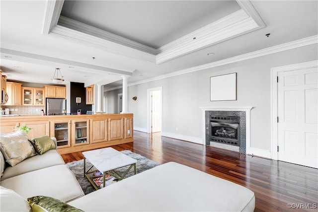 living area with baseboards, a tile fireplace, ornamental molding, dark wood-style flooring, and a tray ceiling