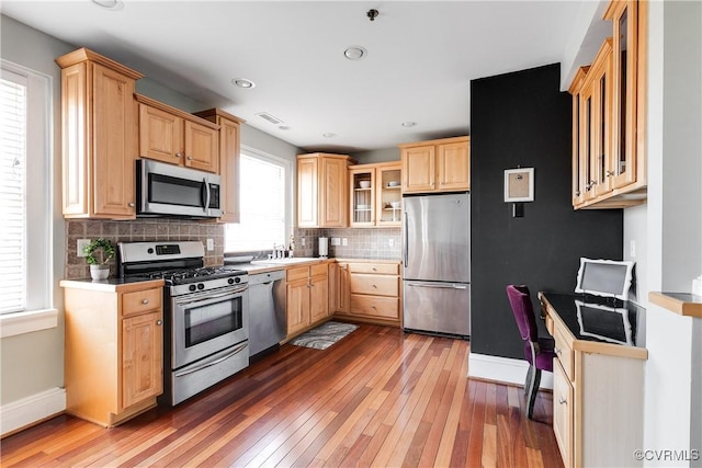 kitchen featuring glass insert cabinets, light brown cabinets, appliances with stainless steel finishes, and dark wood finished floors