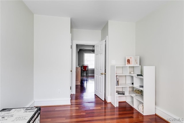 corridor featuring baseboards and dark wood finished floors