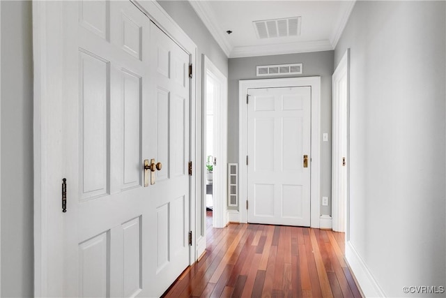 interior space featuring baseboards, crown molding, visible vents, and wood finished floors