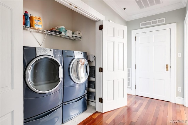 laundry area with laundry area, crown molding, visible vents, and wood finished floors