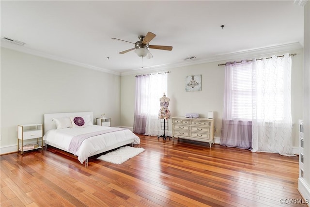 bedroom featuring visible vents, ornamental molding, and wood finished floors