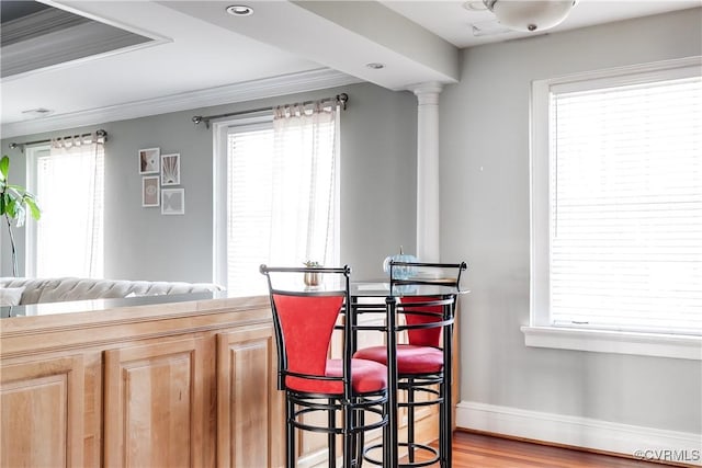 kitchen with crown molding, ornate columns, light wood-style flooring, and baseboards