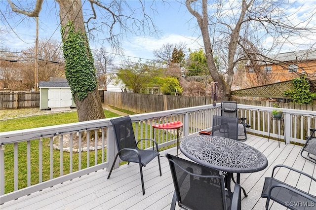 deck featuring a fenced backyard, an outbuilding, a lawn, and a shed