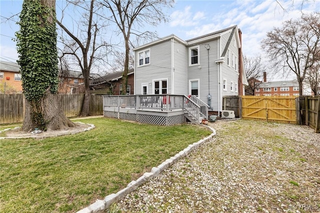 back of house featuring a wooden deck, a yard, a fenced backyard, and a gate