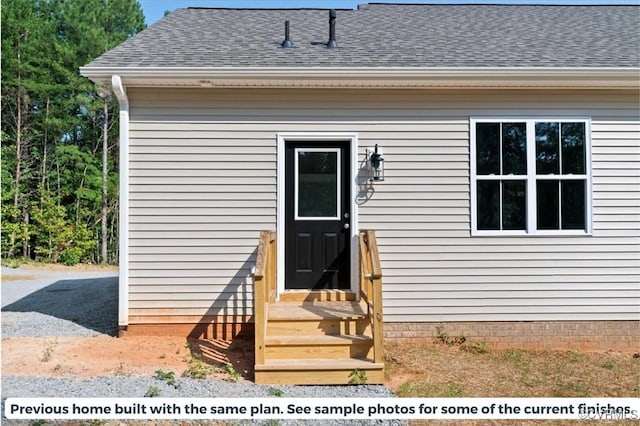 view of exterior entry with roof with shingles