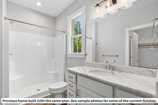 bathroom featuring walk in shower, vanity, and toilet