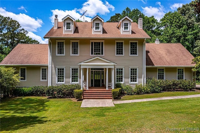 view of front of house featuring a front yard, roof with shingles, and a chimney