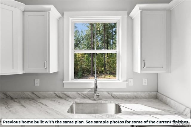 kitchen featuring a sink, white cabinetry, and light stone countertops